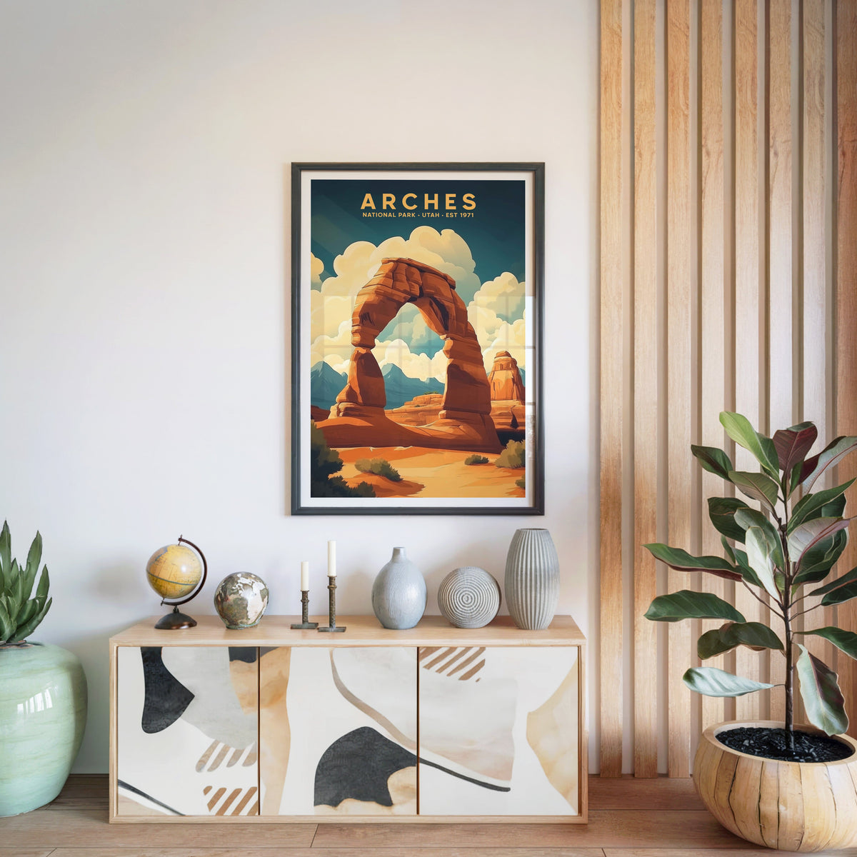 Arches National Park print in a black frame above a light wood sideboard with a globe and ceramic vases
