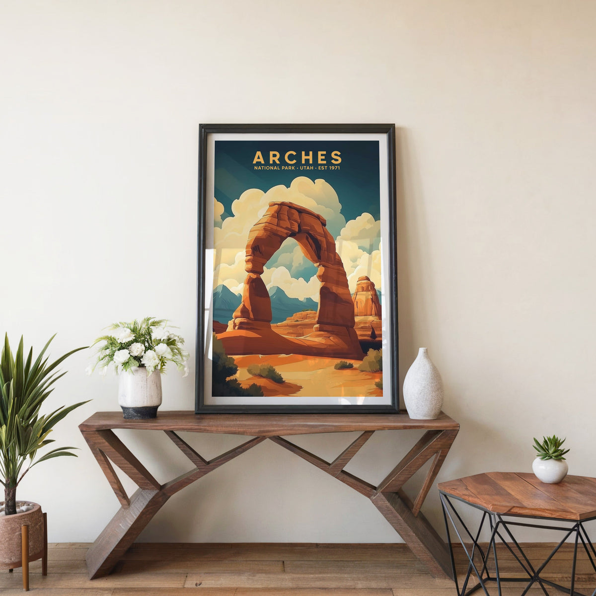 Arches poster in a black frame on an entryway console table beside white flowers and a yucca