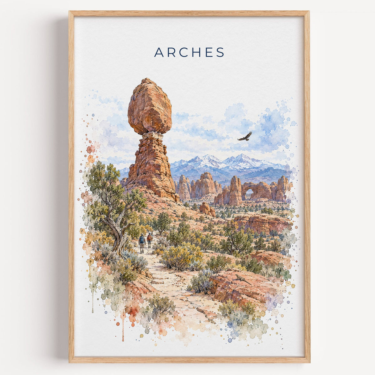 Arches National Park watercolor print in a light oak frame on a plain white wall