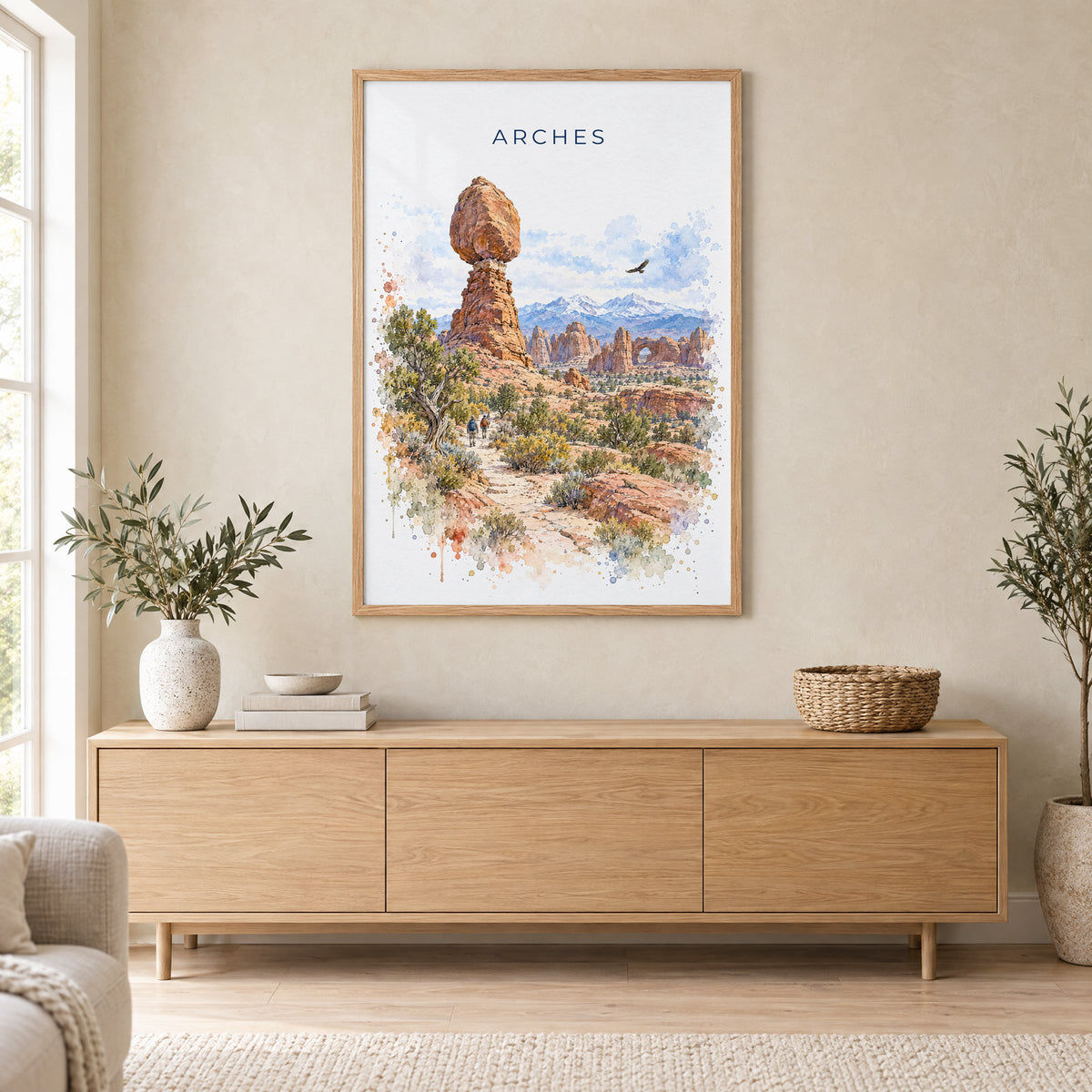 Arches National Park watercolor print in an oak frame above a light wood sideboard in a Scandinavian living room
