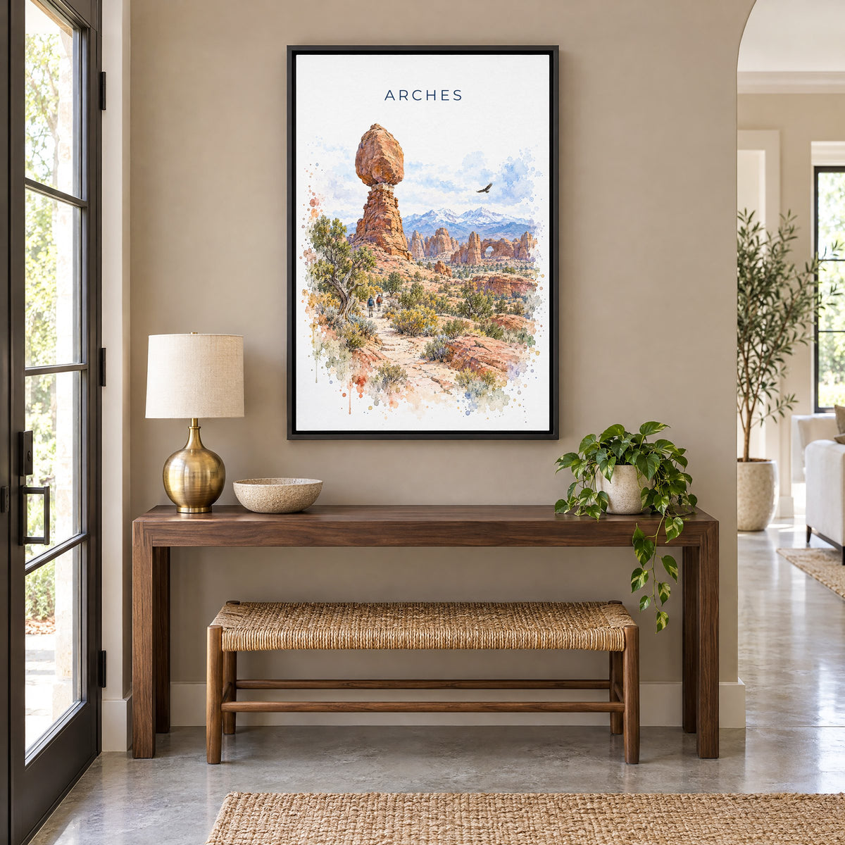 Arches National Park watercolor print as a black floater canvas above a walnut console and woven bench in an entryway