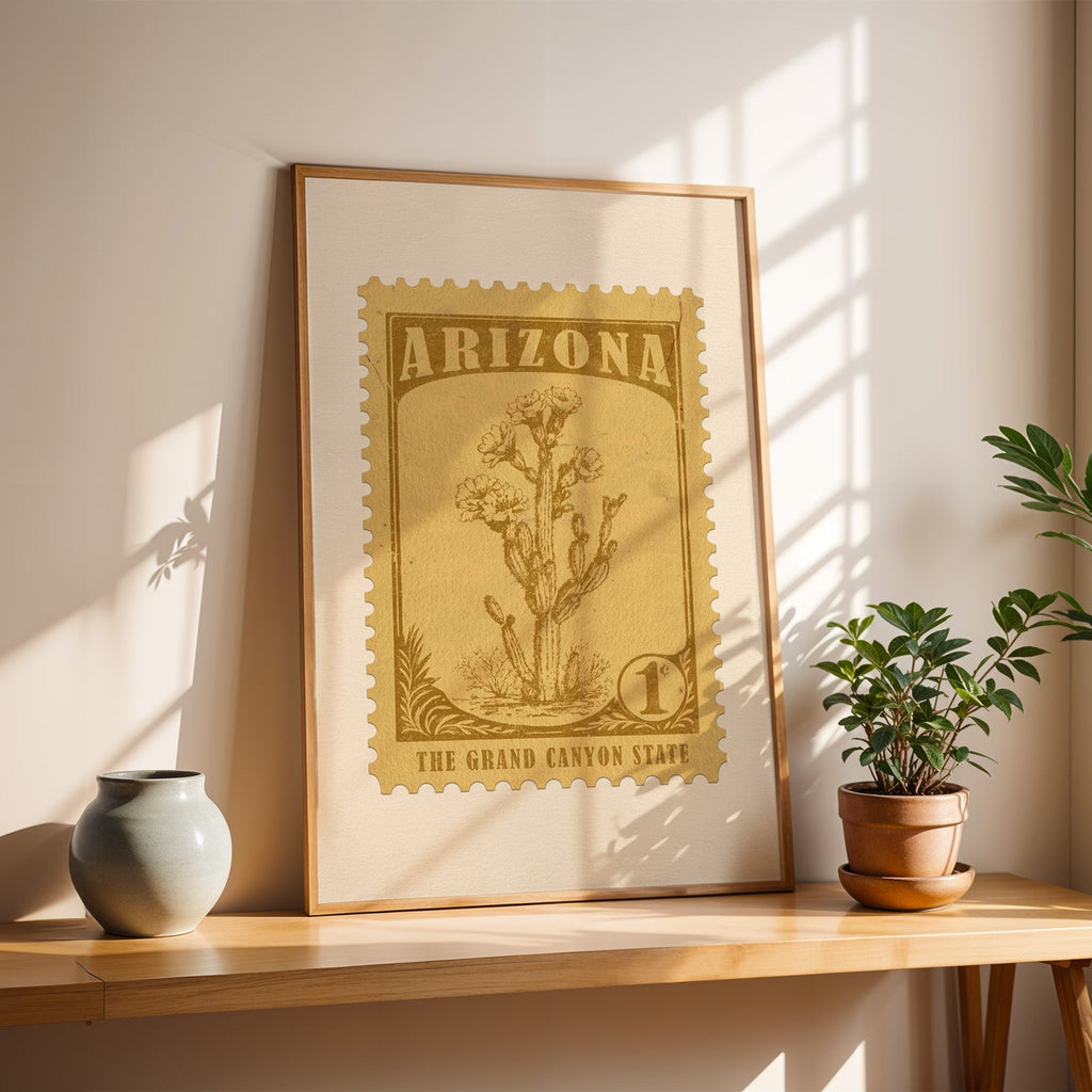 Arizona saguaro blossom stamp print in a light oak frame leaning on a wooden table beside a stoneware vase