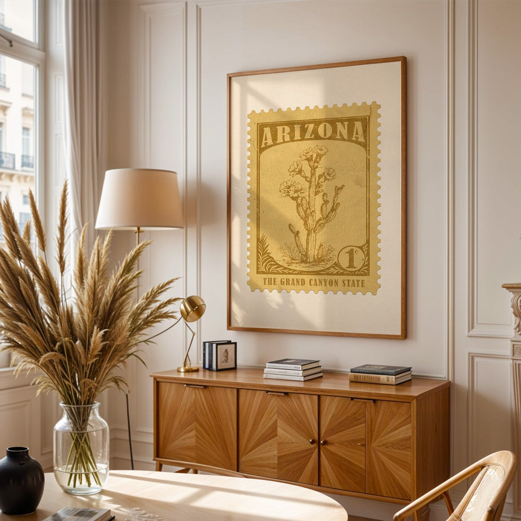 Arizona stamp print framed above a wooden sideboard, pampas grass in a glass vase and a floor lamp alongside