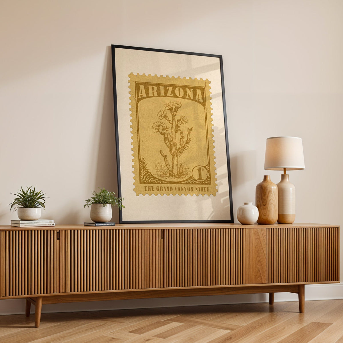 Arizona state flower print in a black frame leaning on a fluted wood credenza with vases and a table lamp