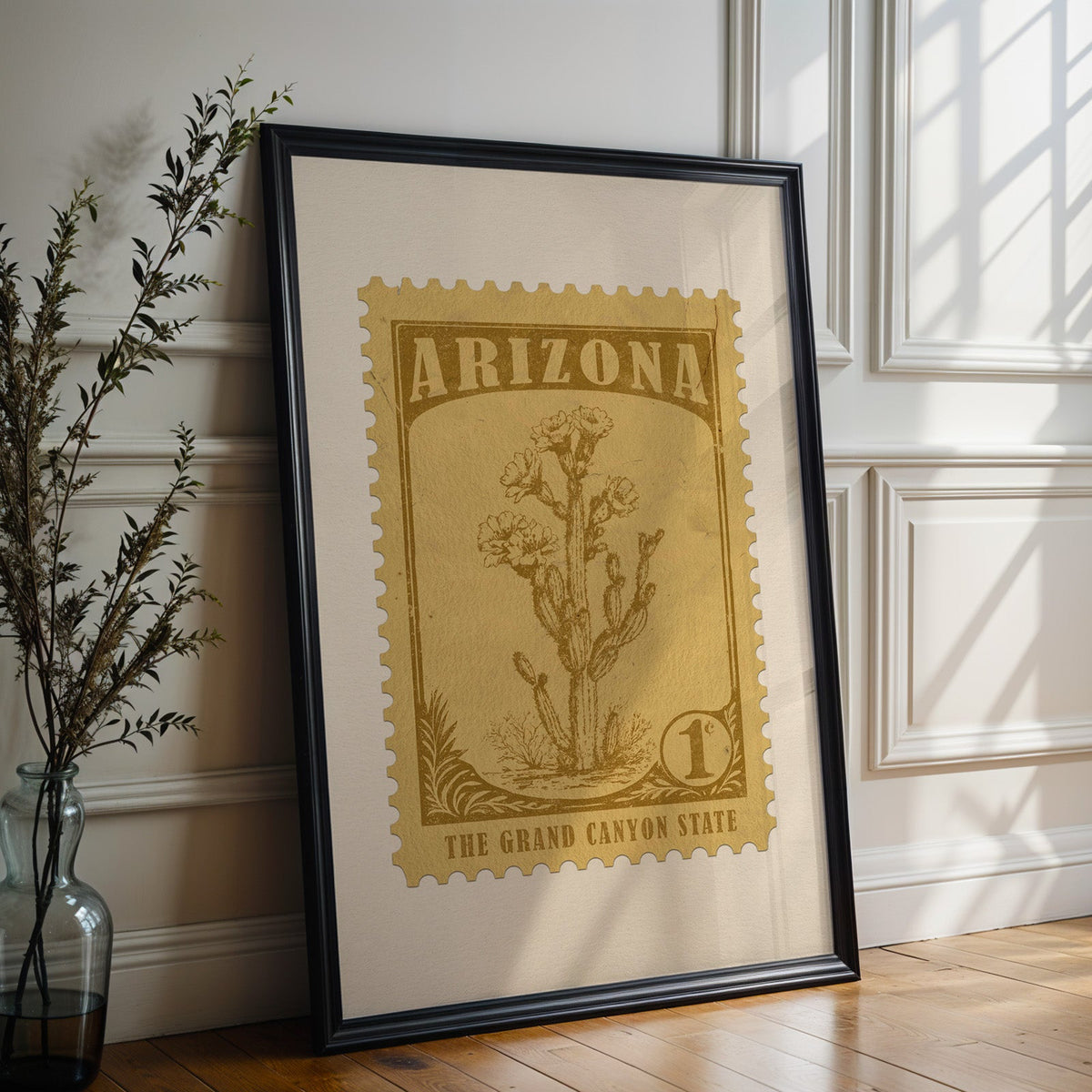 Arizona state flower print in a black frame leaning against a white panelled wall beside olive branches