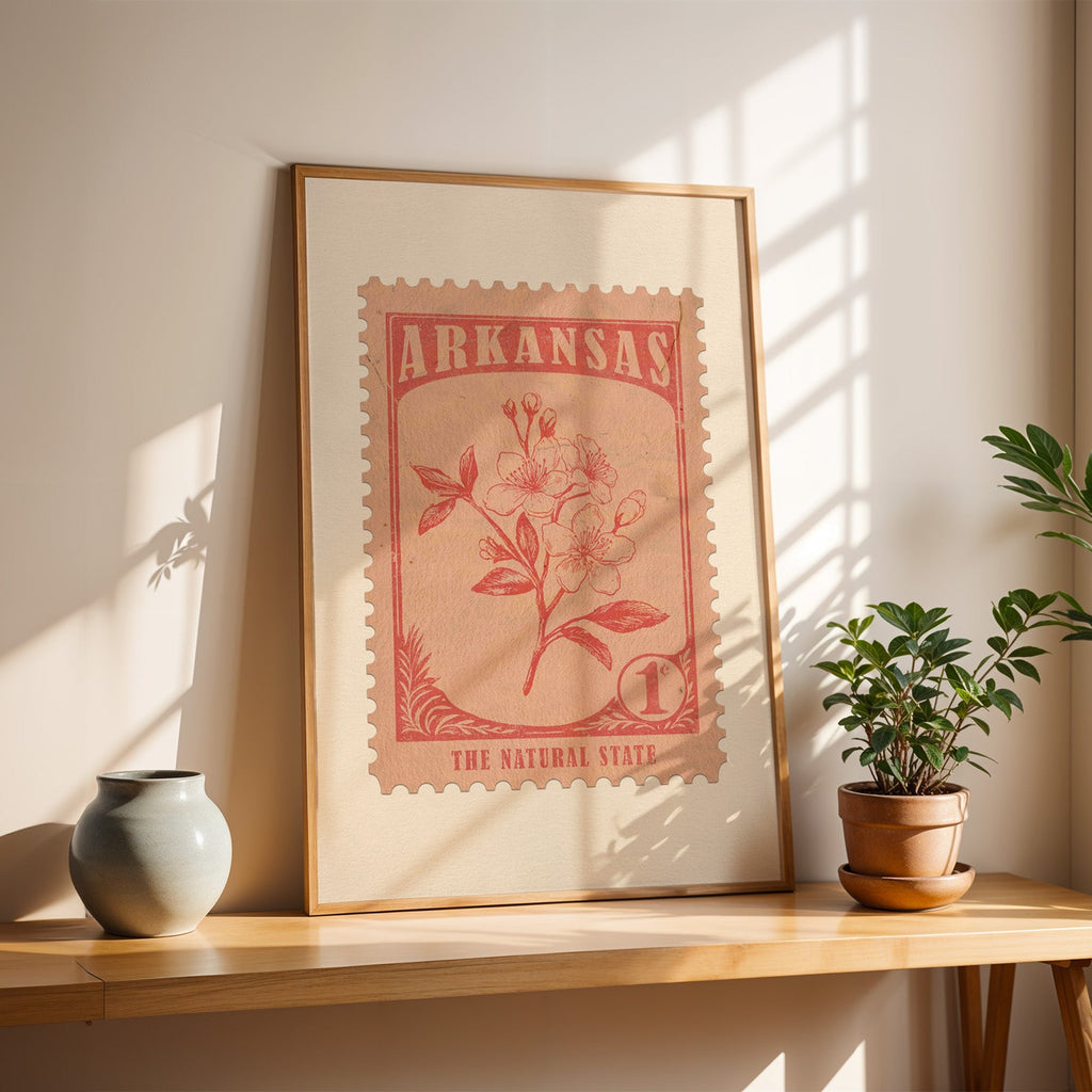 Arkansas apple blossom stamp print in a light oak frame leaning on a wooden table beside a stoneware vase