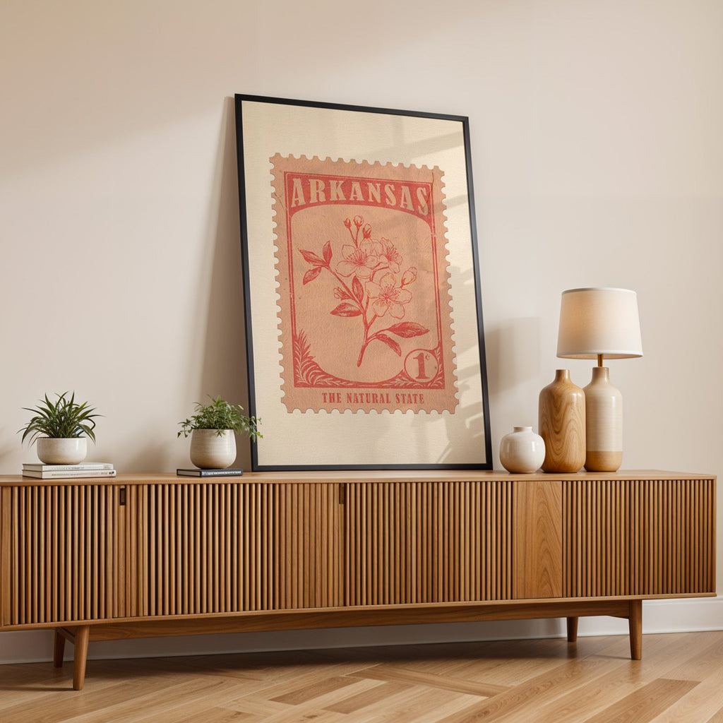 Arkansas state flower print in a black frame leaning on a fluted wood credenza with vases and a table lamp