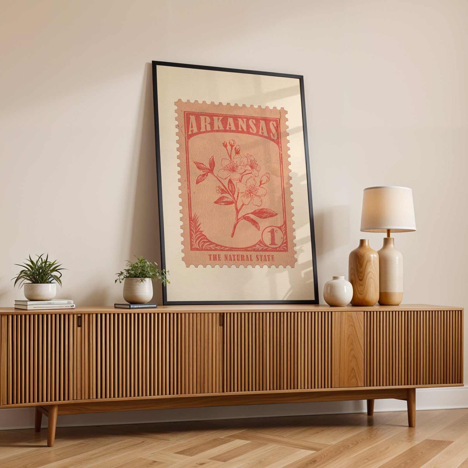 Arkansas state flower print in a black frame leaning on a fluted wood credenza with vases and a table lamp