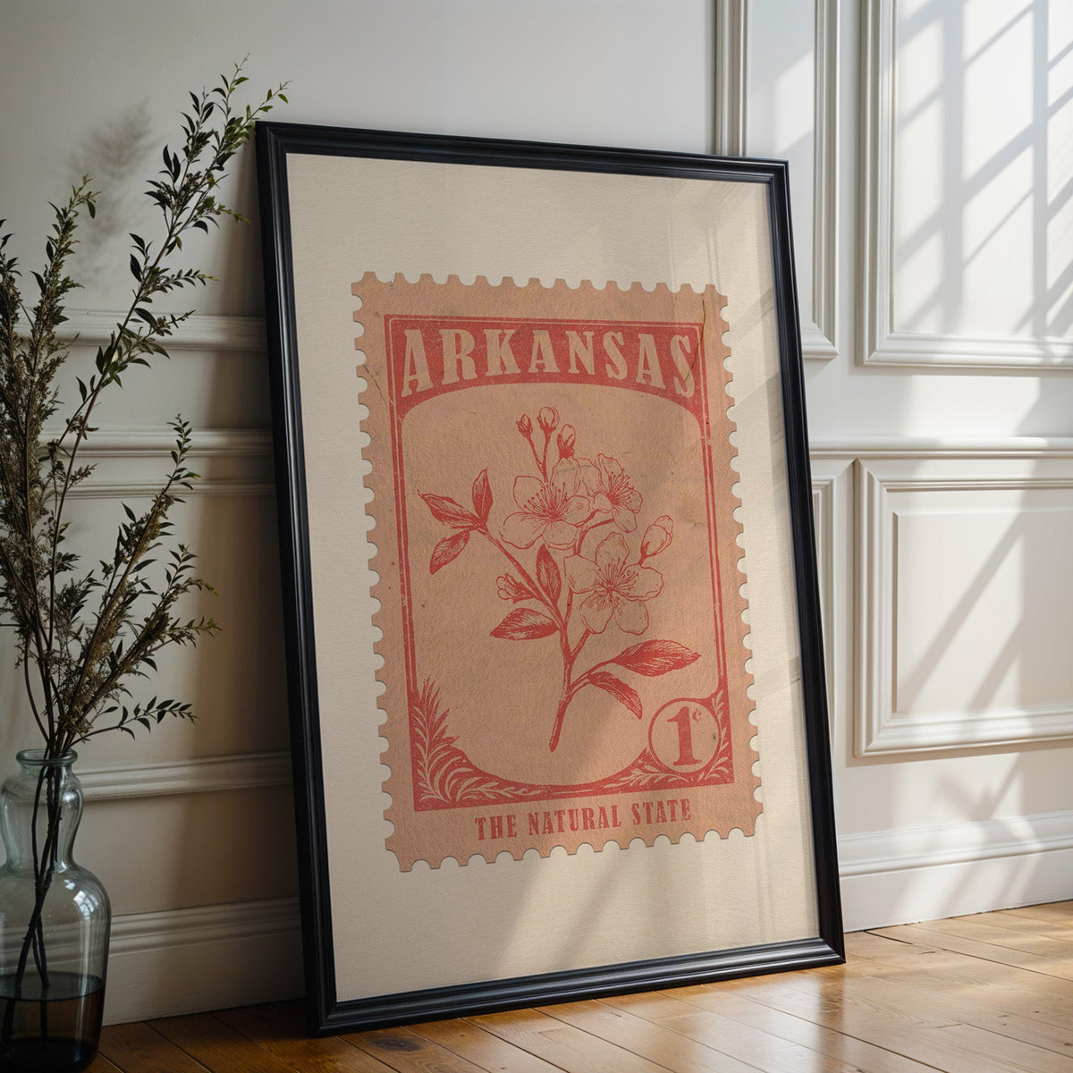 Arkansas state flower print in a black frame leaning against a white panelled wall beside olive branches