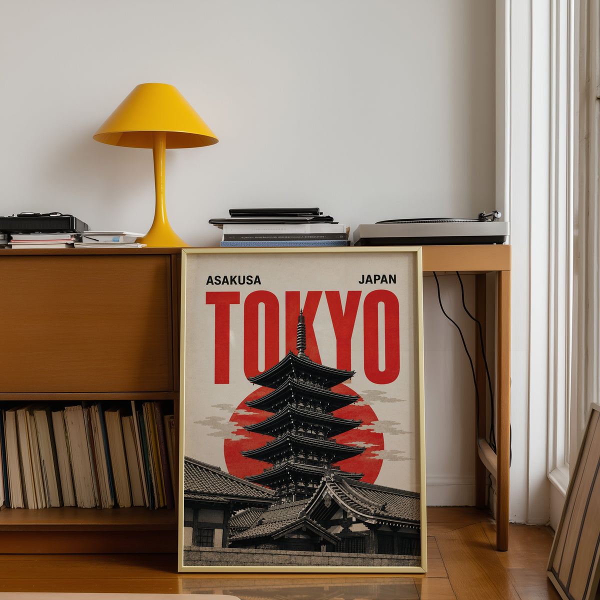 Asakusa Tokyo pagoda poster shown in a gold frame leaning under a teak desk with a yellow lamp