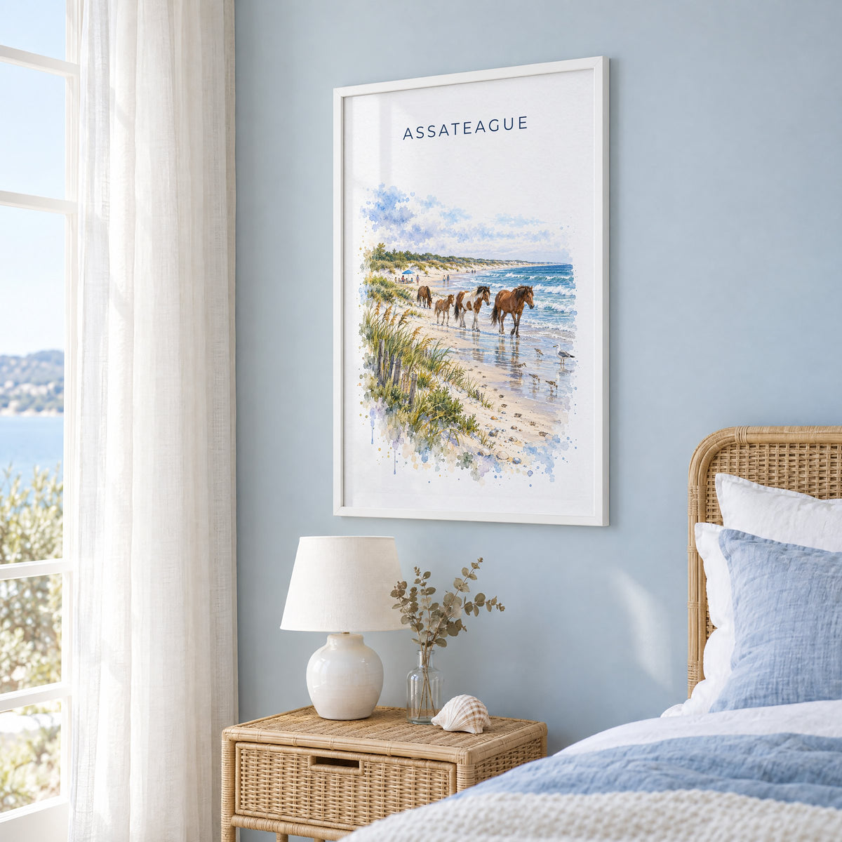 Assateague Island National Seashore watercolor in a white frame on a pale blue wall beside a rattan bed in a coastal bedroom