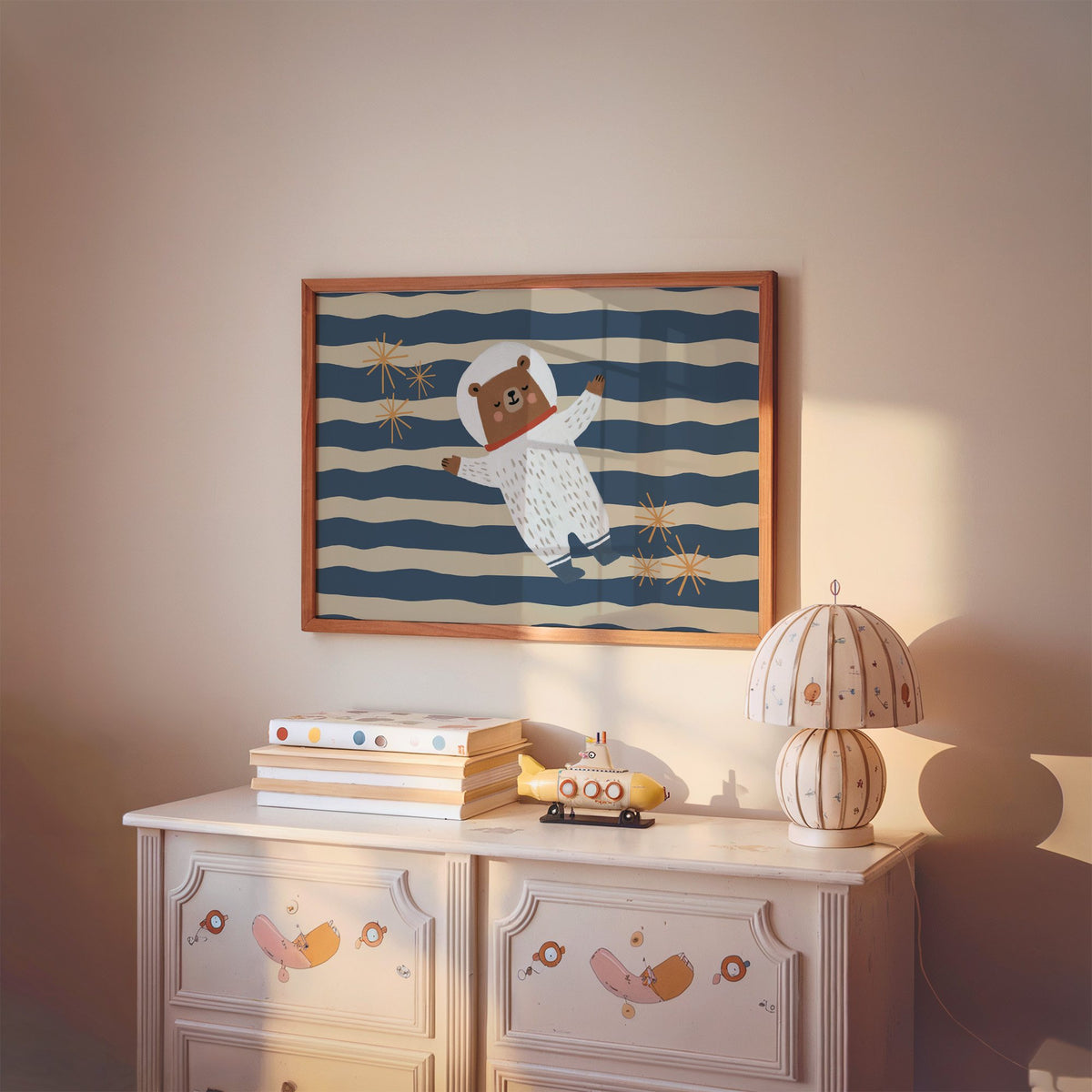 Landscape astronaut bear wavy stripe nursery print in a cherry wood frame above a painted dresser and lamp