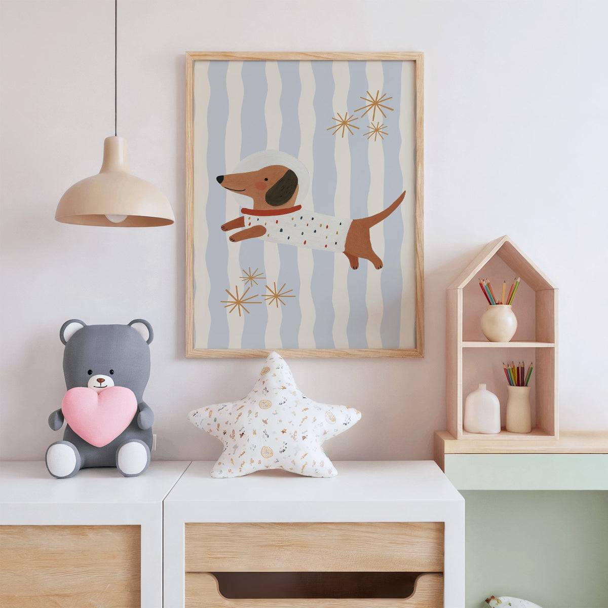 Astronaut dachshund wavy stripe nursery print in an oak frame above a white dresser with a star pillow and house shelf