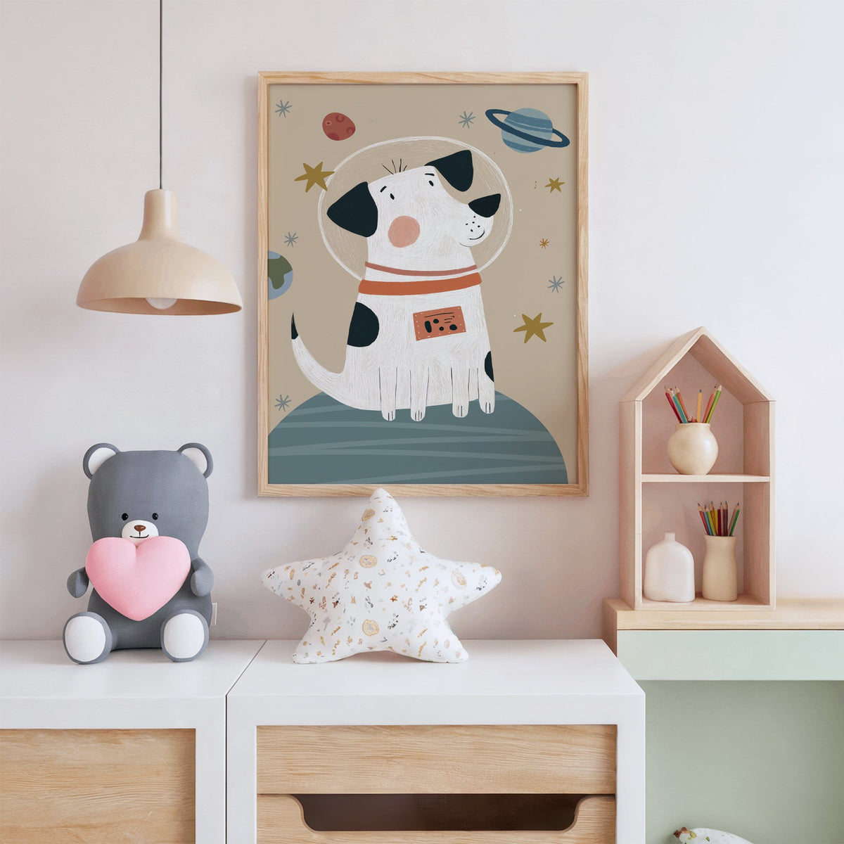 Spotted dog astronaut planet nursery print in an oak frame above a white dresser with a star pillow and house shelf