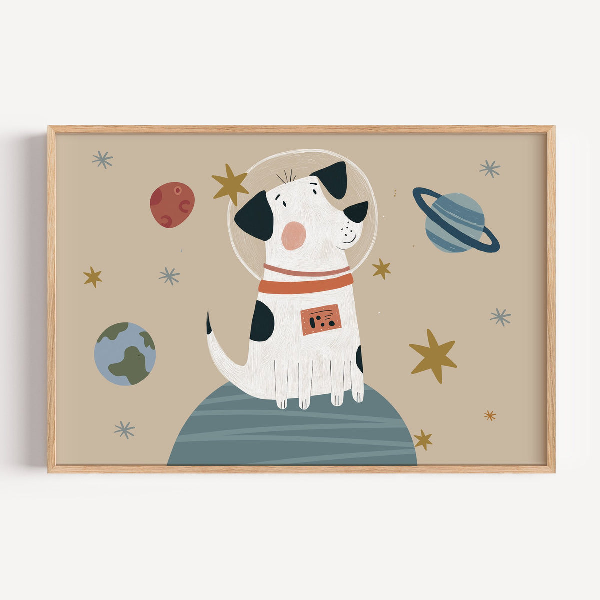 Landscape spotted dog astronaut planet nursery print in a light oak frame on a plain white wall