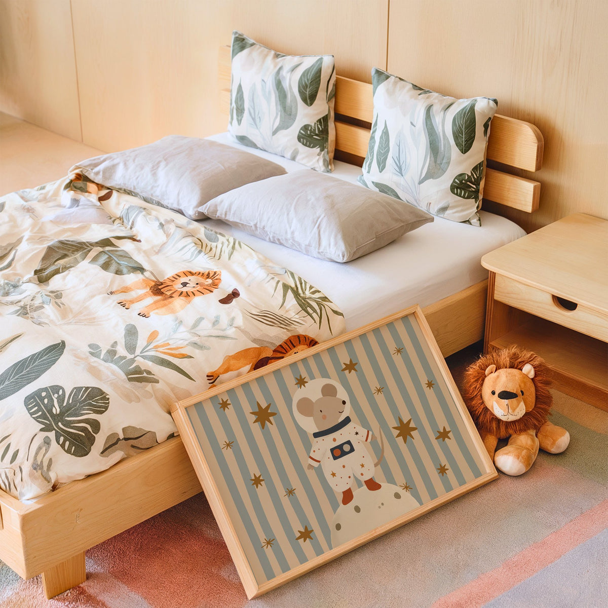 Landscape astronaut mouse on the moon nursery print in an oak frame leaning on a kids bed by a lion plush