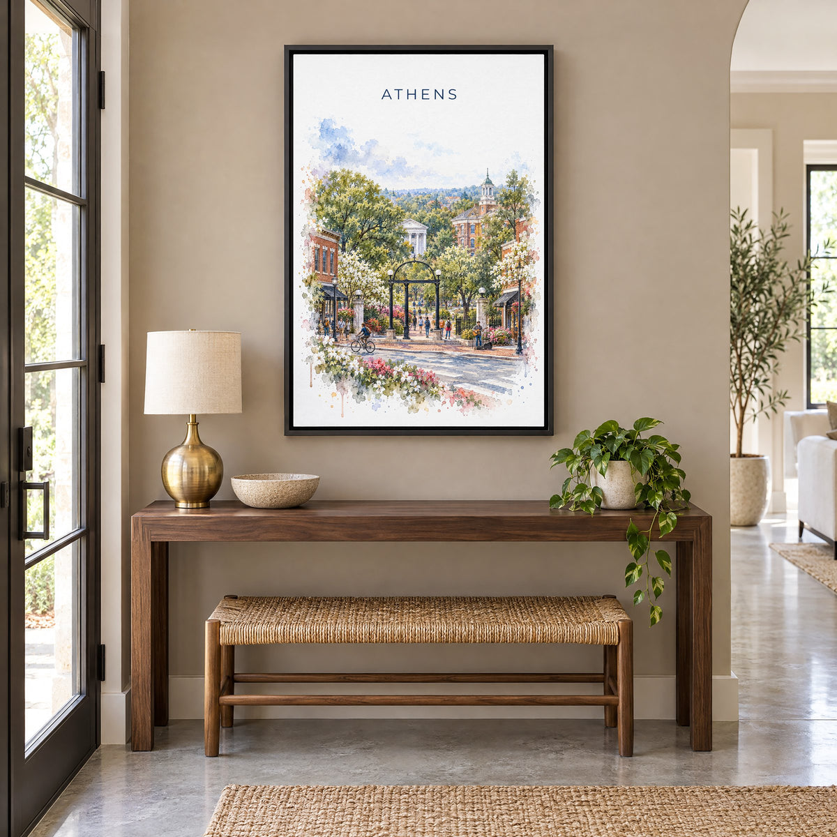 Athens, Georgia watercolor print as a black floater canvas above a walnut console and woven bench in an entryway
