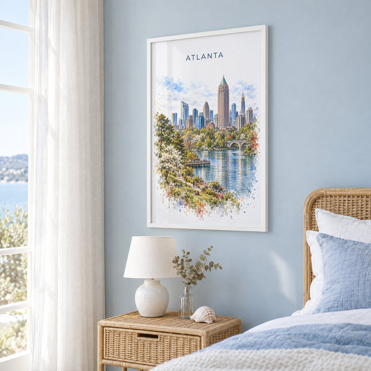 Atlanta watercolor print in a white frame on a pale blue wall beside a rattan bed in a coastal bedroom