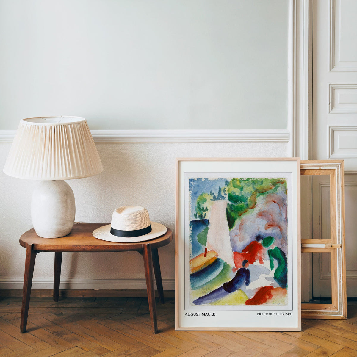 Macke poster in a light wood frame leaning by a bench and panama hat