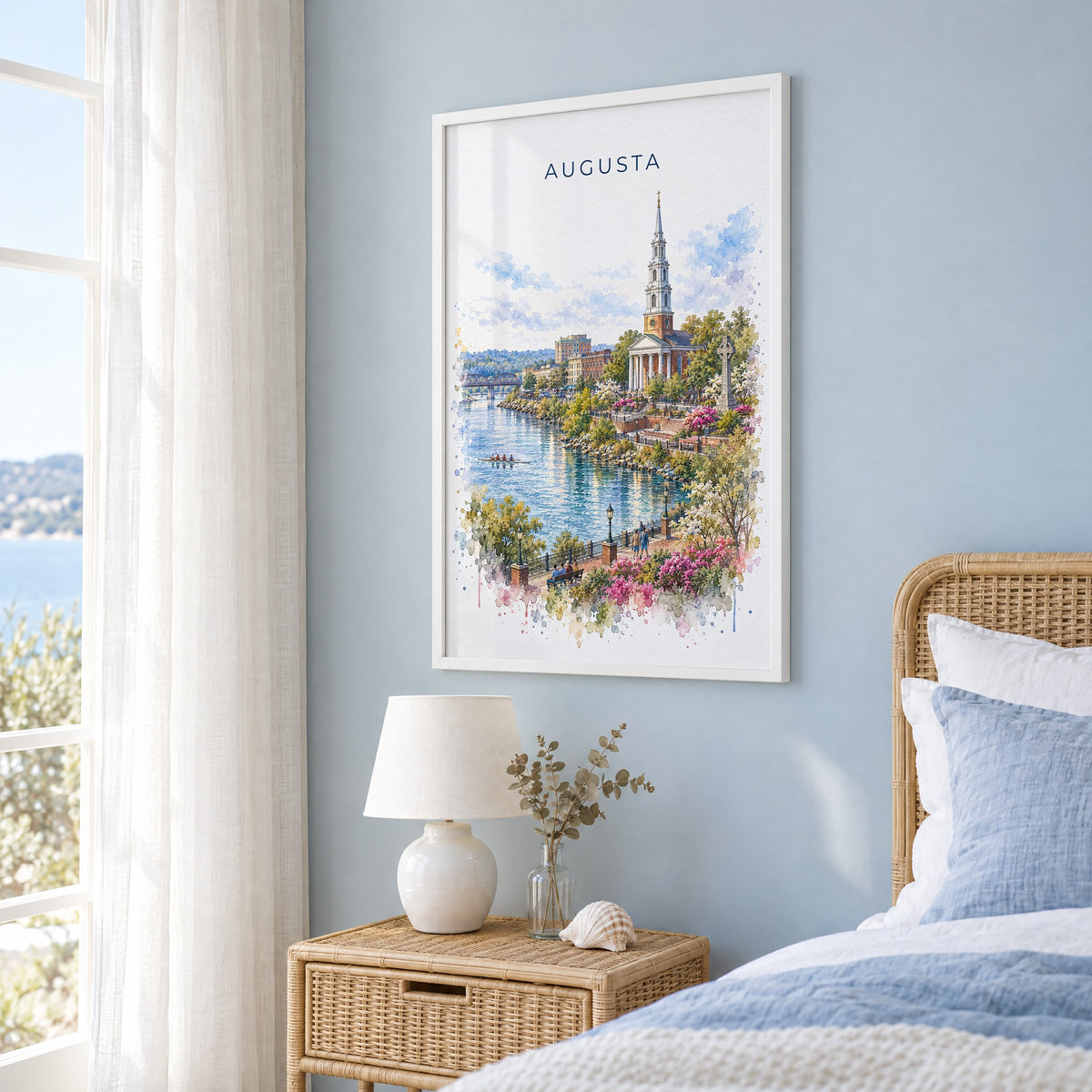 Augusta, Georgia watercolor print in a white frame on a pale blue wall beside a rattan bed in a coastal bedroom