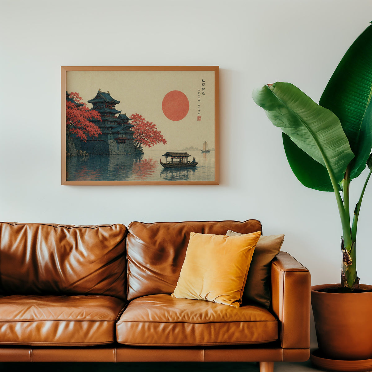 Autumn castle on a lake with red sun print in a warm oak frame above a cognac leather sofa with a mustard pillow