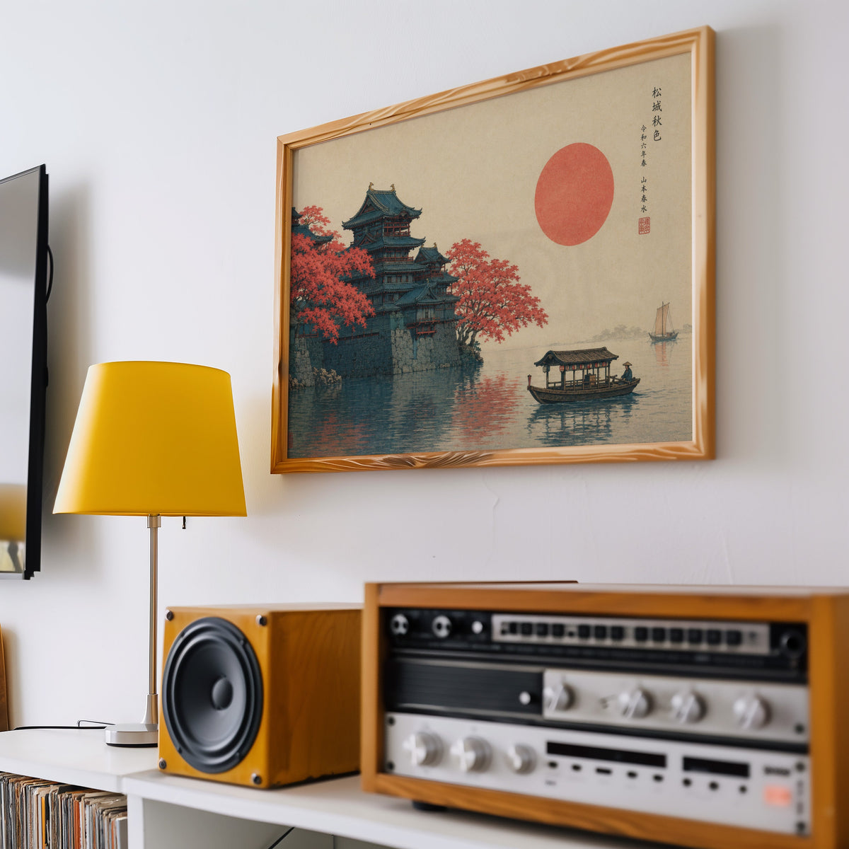 Autumn castle on a lake with red sun print in a pine frame above a vintage stereo and a yellow table lamp