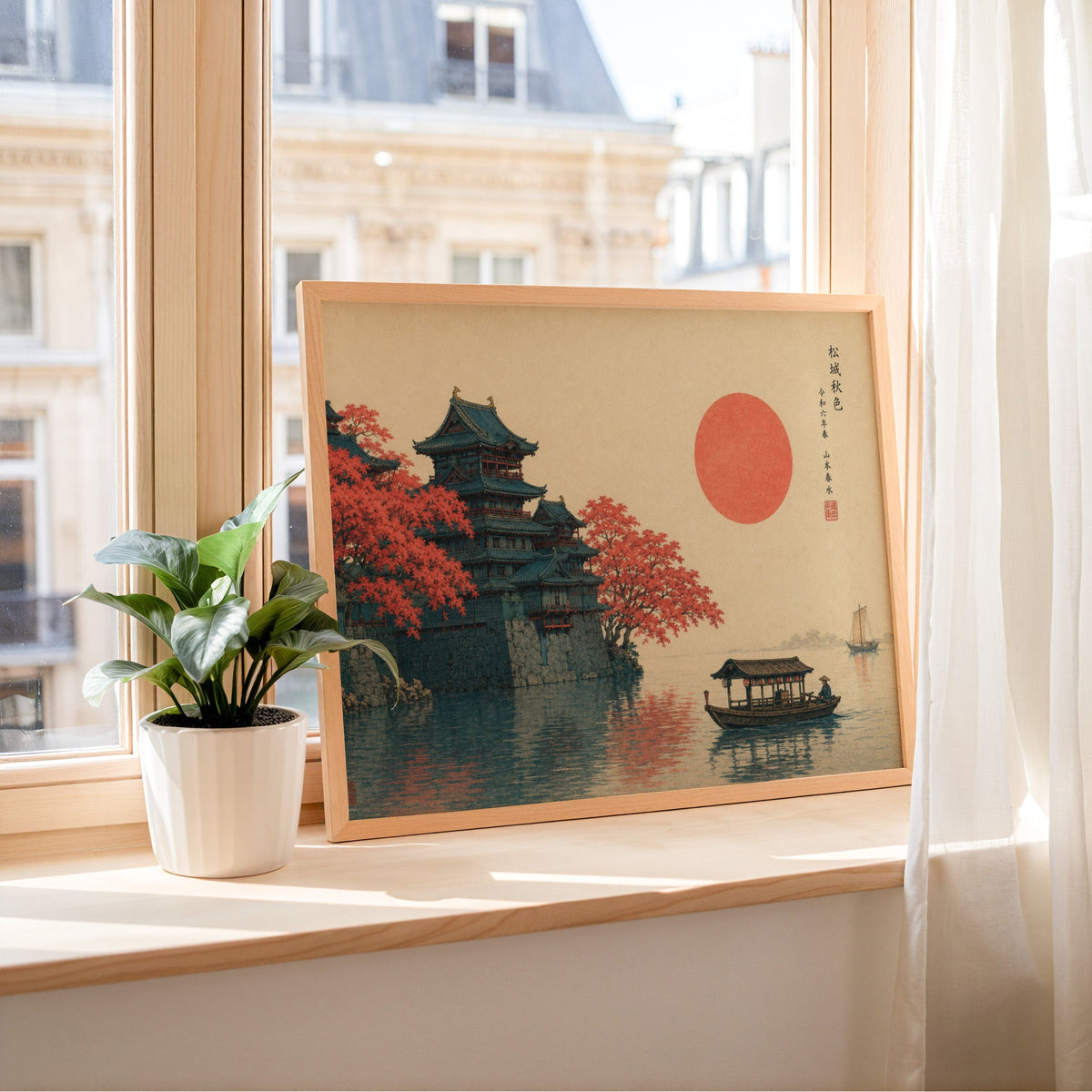 Autumn castle on a lake with red sun print in a light wood frame leaning on a sunny windowsill by sheer curtains