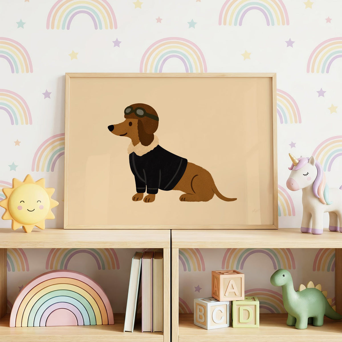 Dachshund in aviator cap nursery print in an oak frame on a toy shelf against rainbow wallpaper
