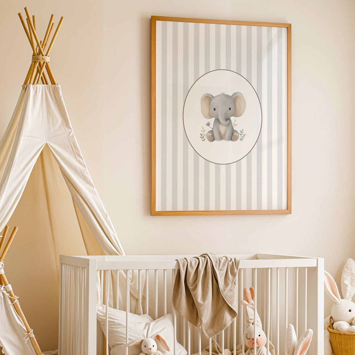 Baby elephant in a cream oval on grey stripes nursery print in an oak frame above a white crib beside a canvas teepee