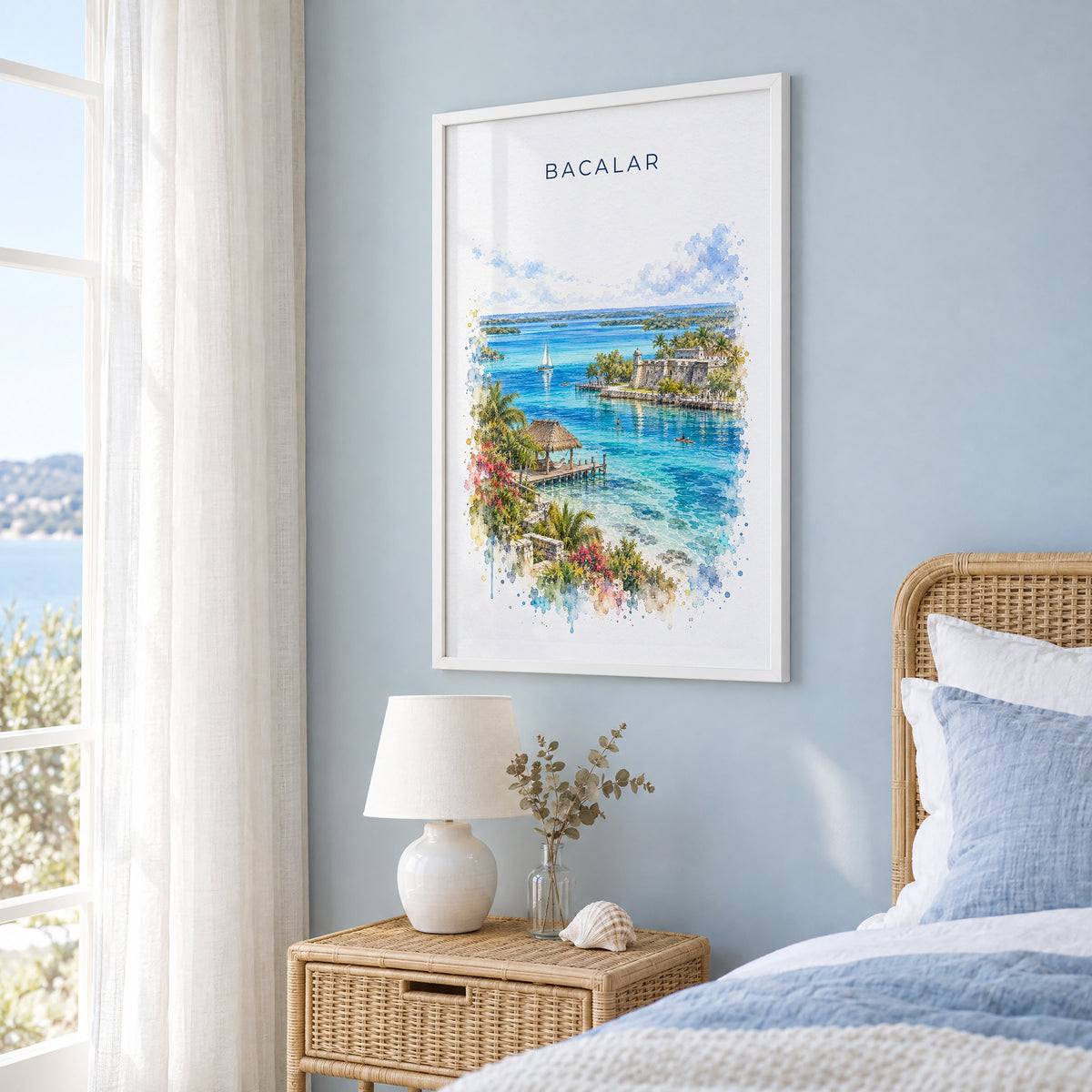 Bacalar watercolor print in a white frame on a pale blue wall beside a rattan bed in a coastal bedroom