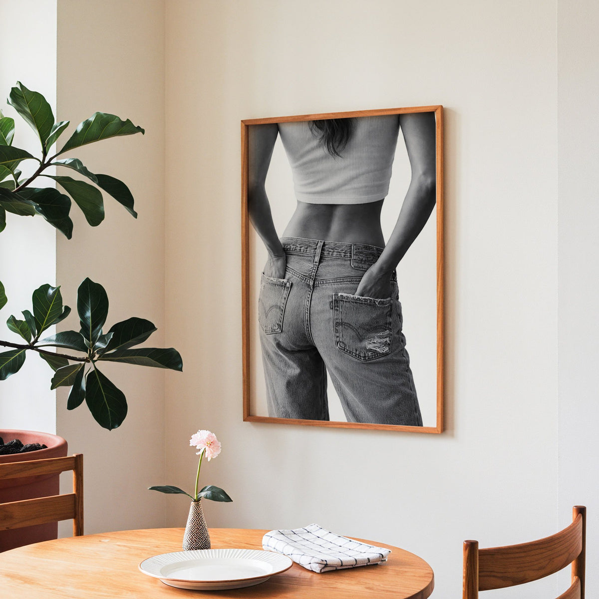 Hands in back pockets of distressed jeans print in a teak frame above a round wooden dining table