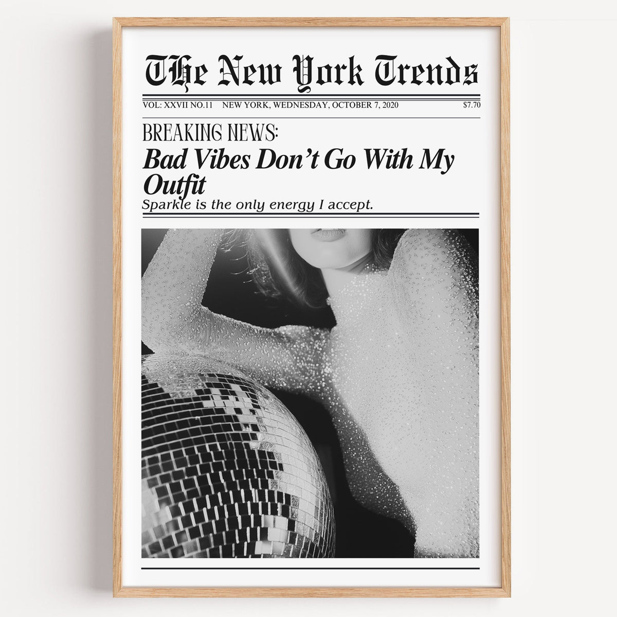 Sequin top and disco ball mock newspaper print in a light oak frame on a plain white wall