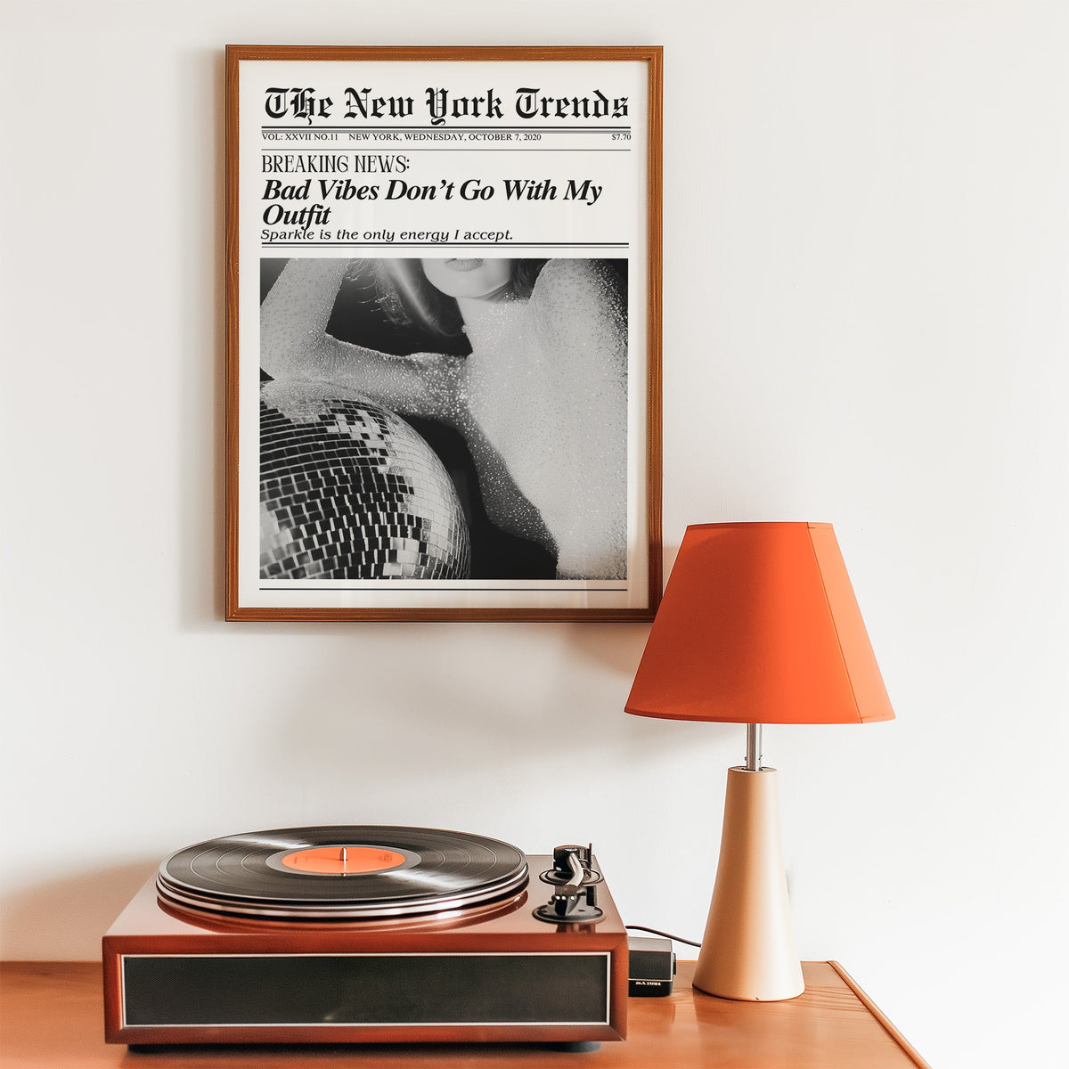 Sequin top and disco ball mock newspaper print in a walnut frame above a record player and orange lamp