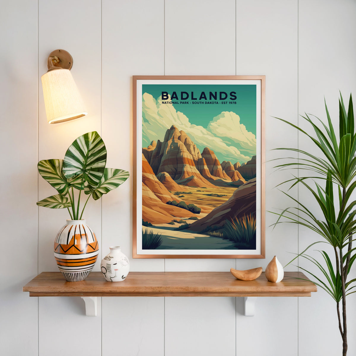 Badlands National Park print in a copper frame above an oak shelf on white shiplap with a sconce