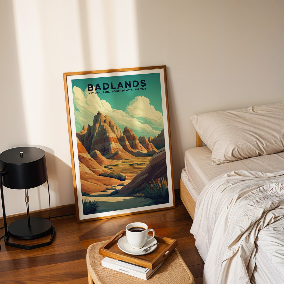 Badlands National Park print in an oak frame leaning on a bedroom floor beside the bed and a tray