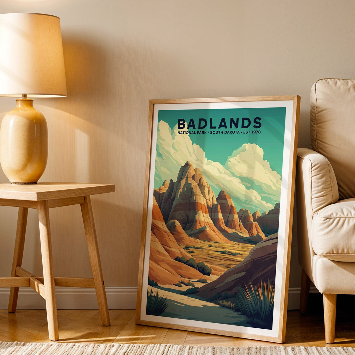 Badlands print in an oak frame beside a cream armchair and an amber lamp in warm afternoon light
