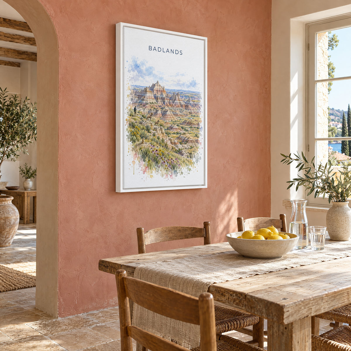 Badlands National Park watercolor print as a white floater canvas on a terracotta wall above a rustic dining table
