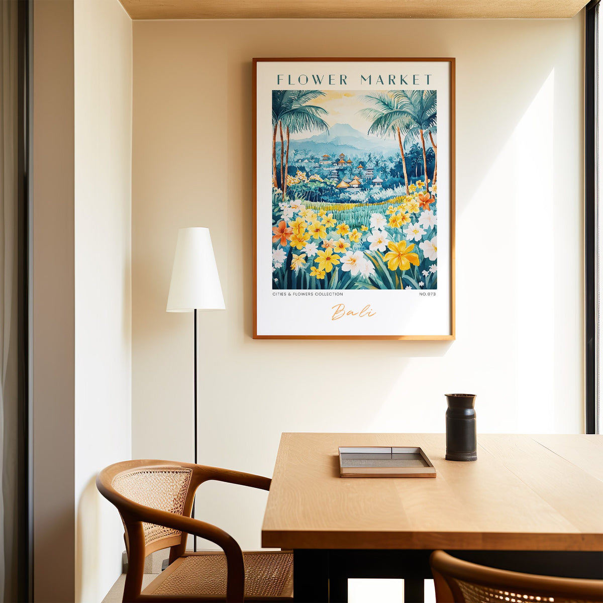 Bali flower market print in an oak frame above a dining table and cane chair