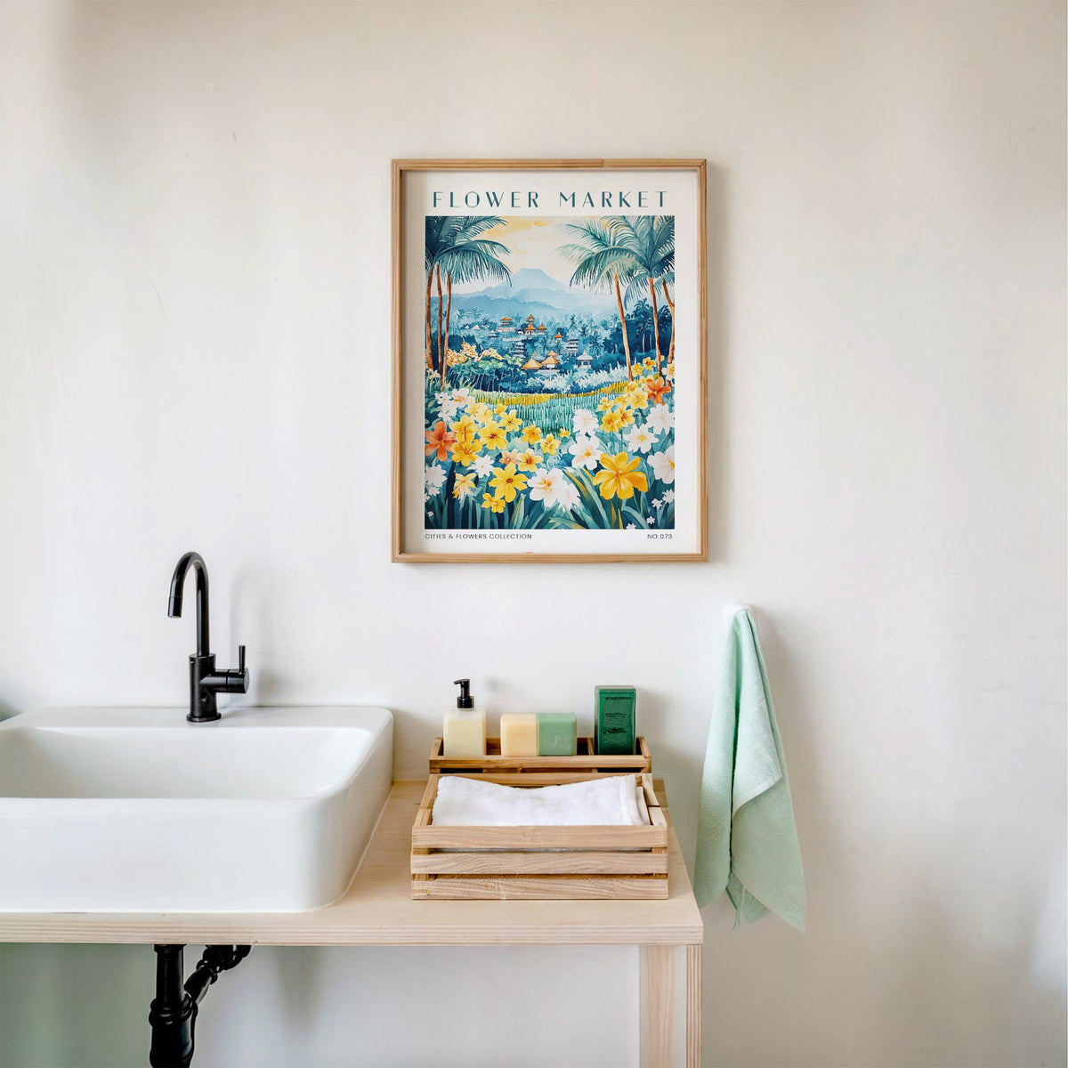 Bali flower market print in an oak frame above a white bathroom sink with folded towels