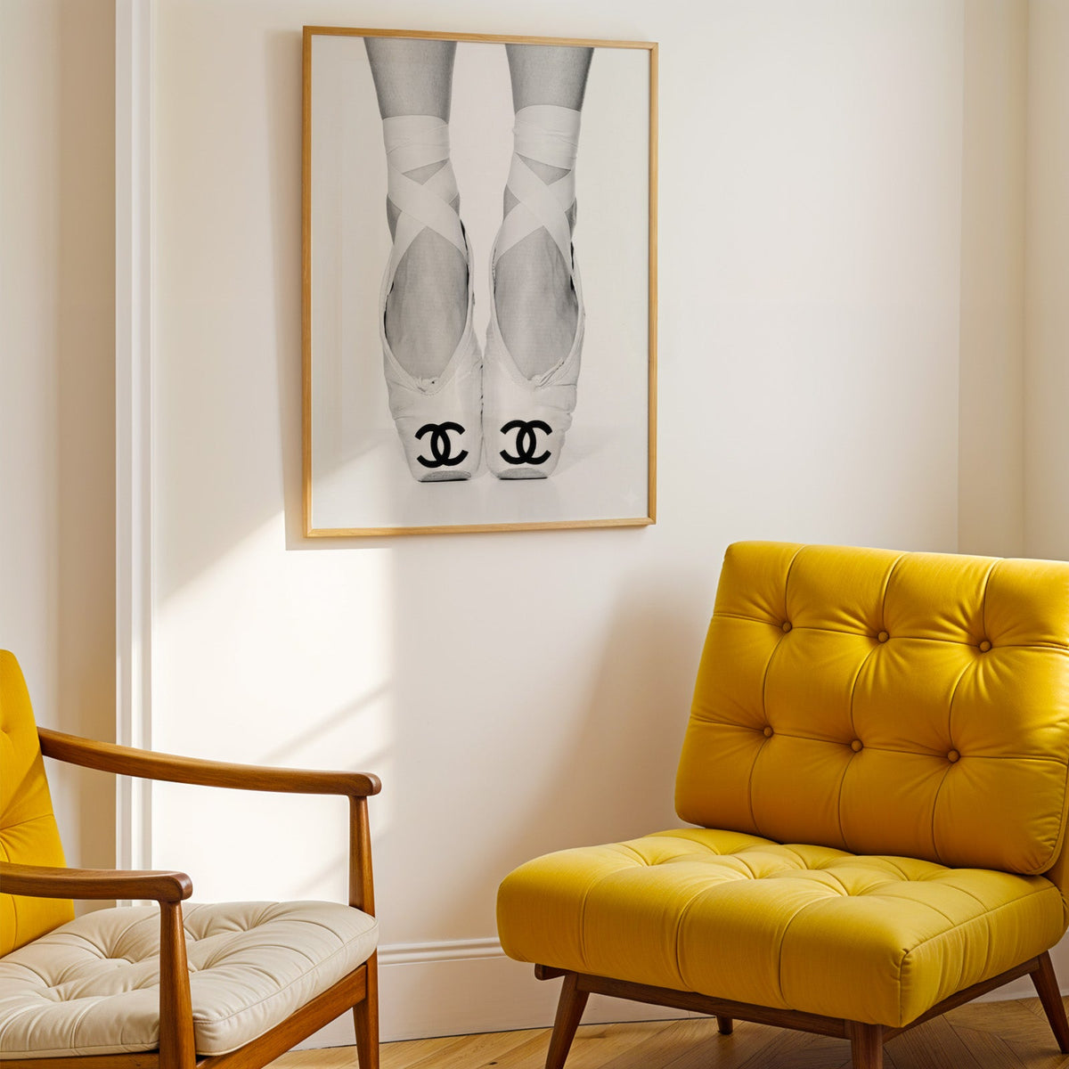 White ballet pointe shoes with crossed ribbons print shown in a gold frame above a mustard yellow tufted armchair