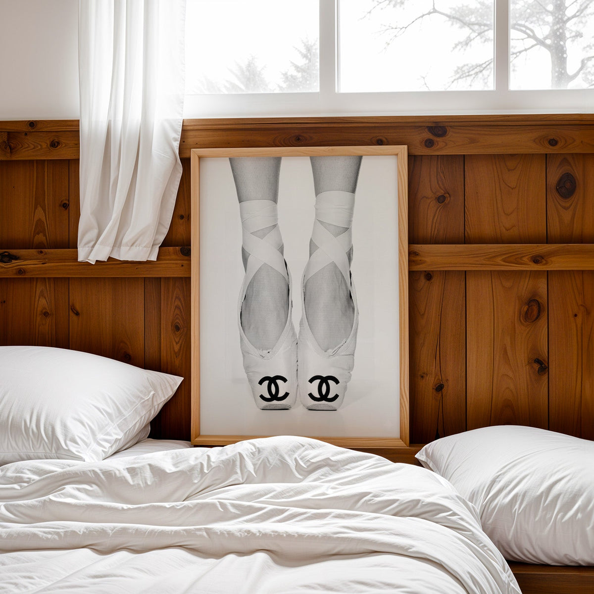 White ballet pointe shoes with crossed ribbons print in a pine frame leaning on a wood headboard over white bedding