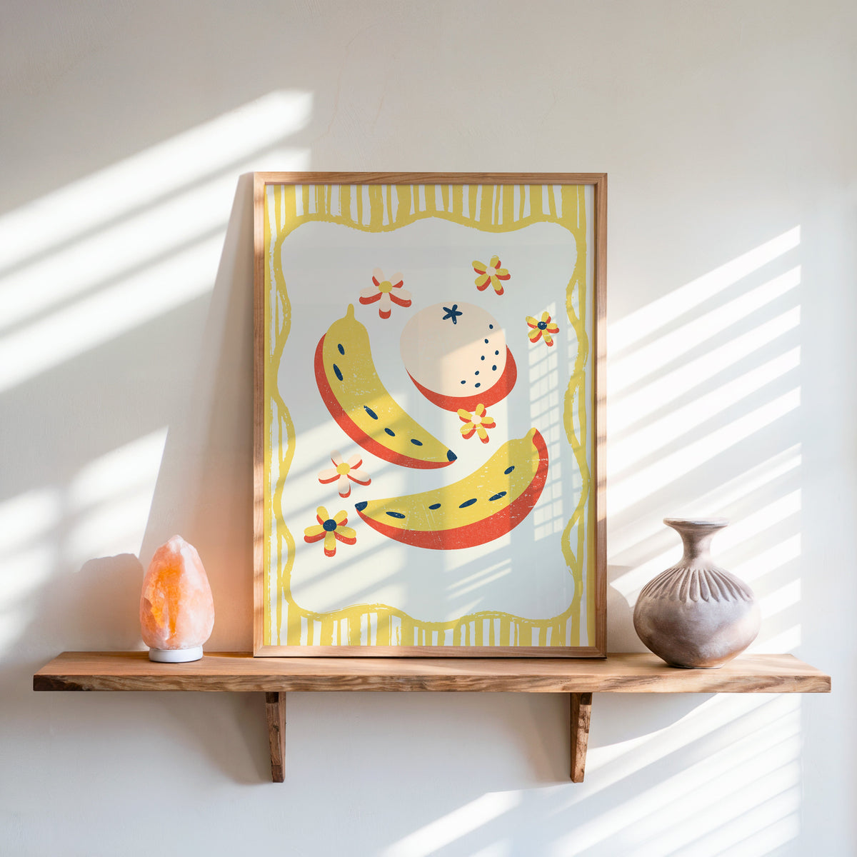 Banana and peach print in an oak frame on a live-edge shelf beside a salt lamp