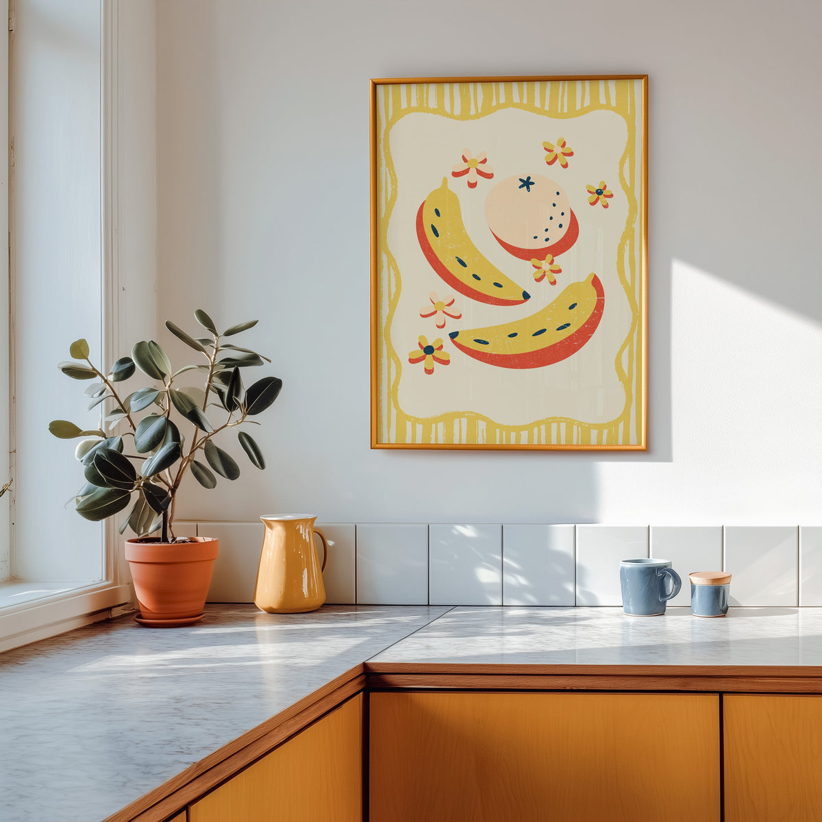 Banana and peach print shown in a gold frame above a marble counter in a tan kitchen