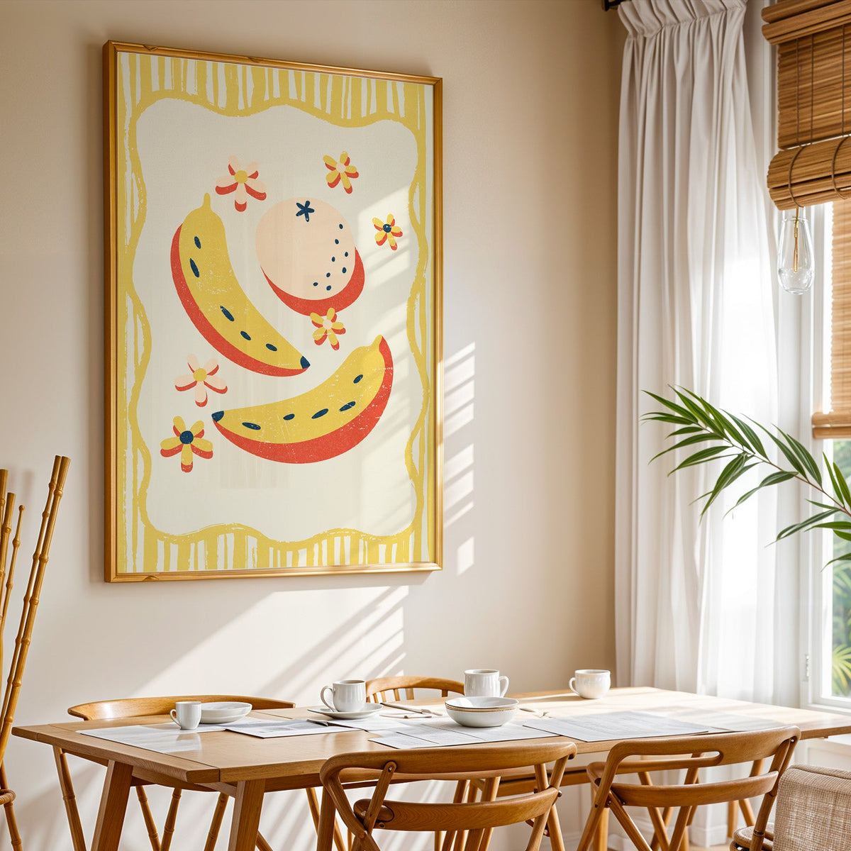 Banana and peach print shown in a gold frame above a breakfast table by a curtained window