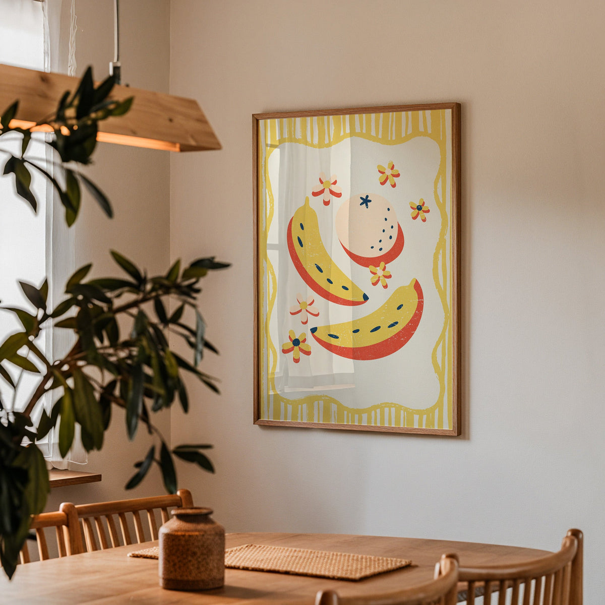 Banana and peach print in a walnut frame above a dining table with olive branches