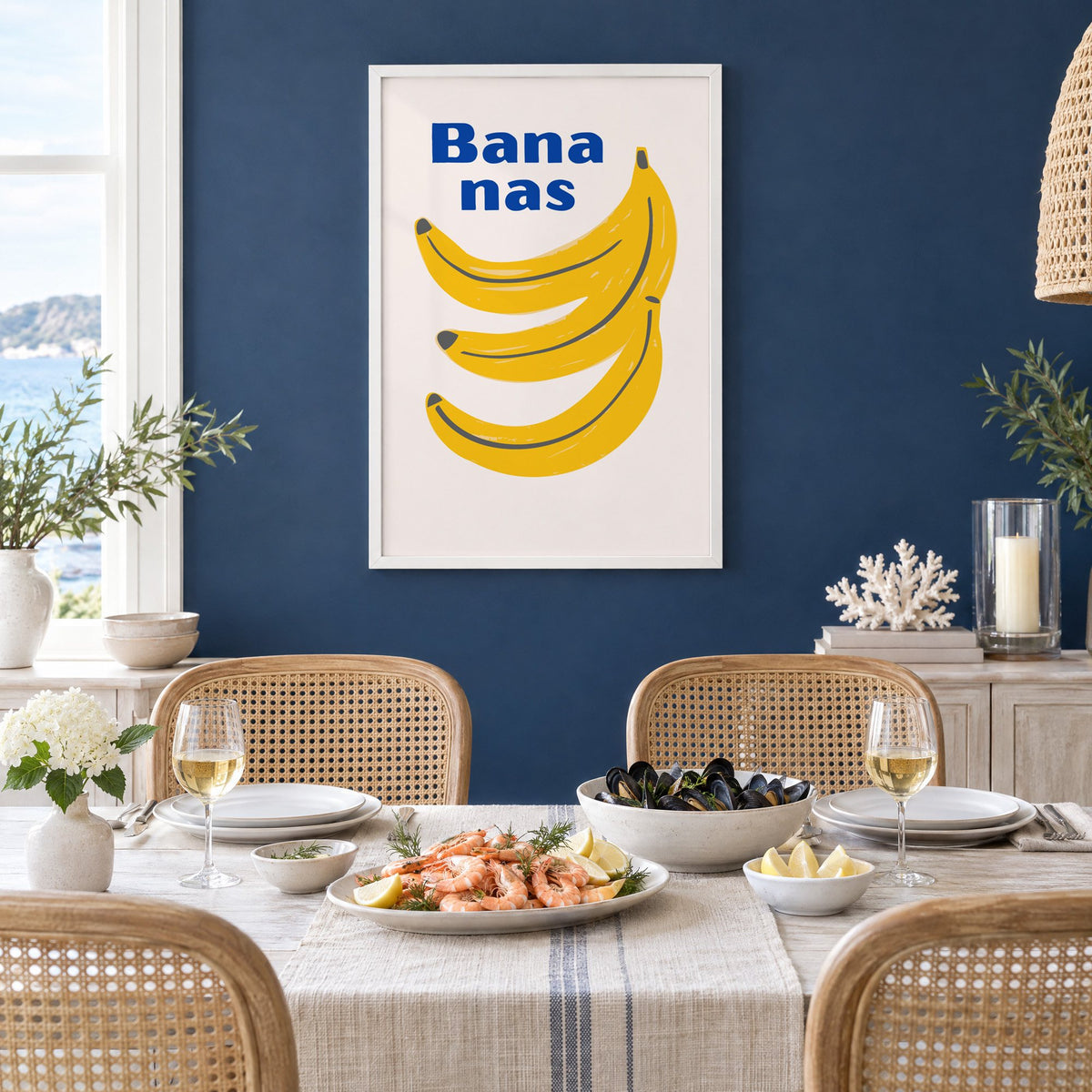 Bana nas blue type banana bunch print in a white frame on a navy wall above a dining table set with shrimp and mussels