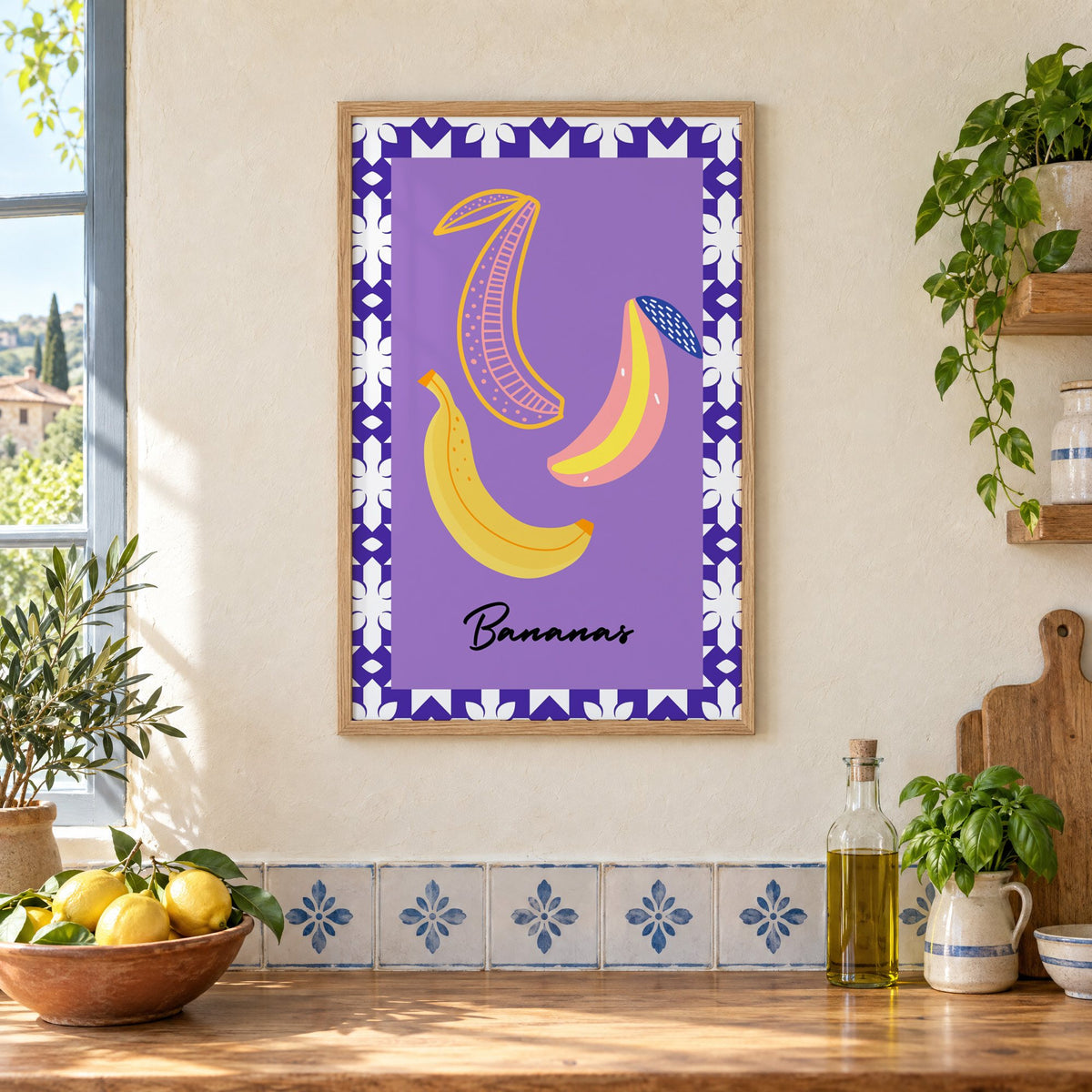 Bananas doodle lavender tile border print in an oak frame on a cream plaster wall above a worktop with a bowl of lemons and blue-and-white tiles