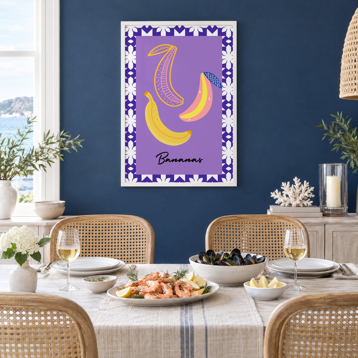 Bananas doodle lavender tile border print in a white frame on a navy wall above a dining table set with shrimp and mussels