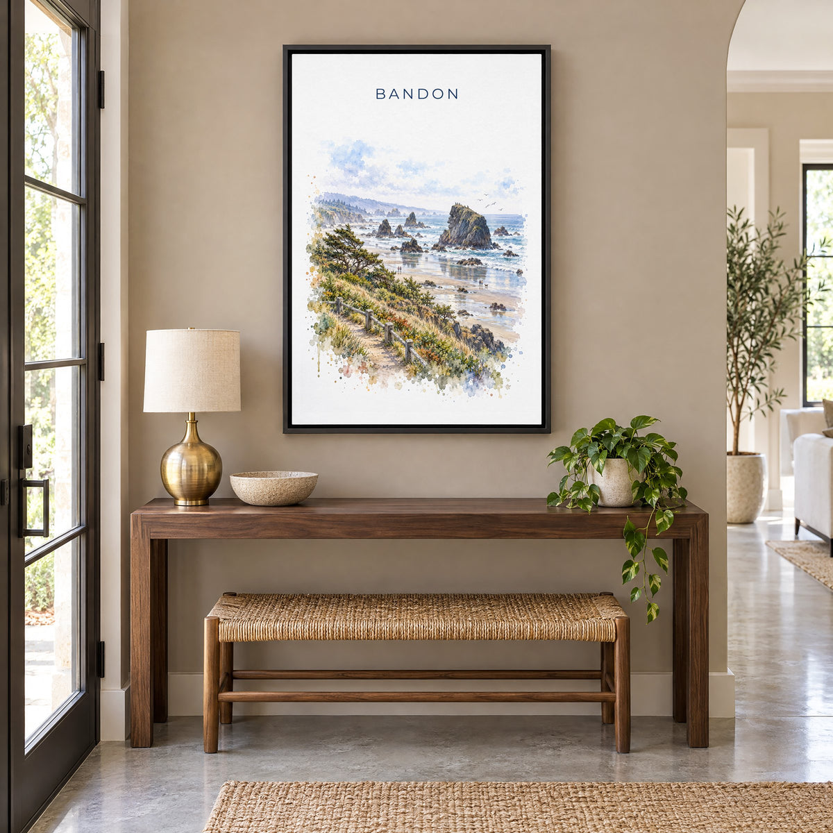 Bandon, Oregon watercolor print as a black floater canvas above a walnut console and woven bench in an entryway