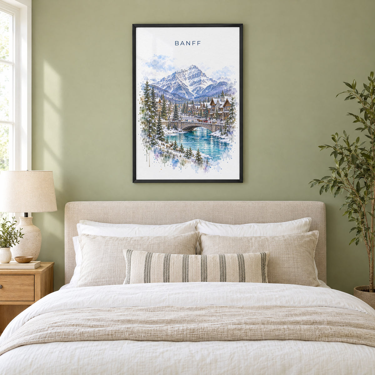 Banff watercolor print in a black frame above an upholstered headboard in a sage green bedroom